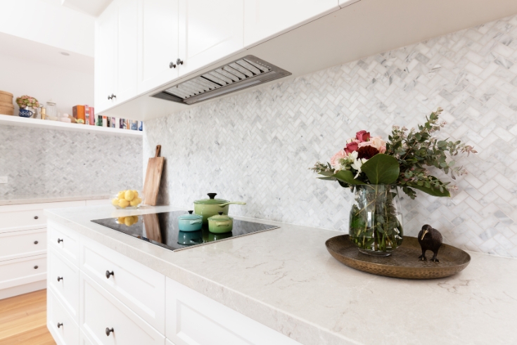 All-white kitchen counter with flowers and a few small pots on the stovetop.