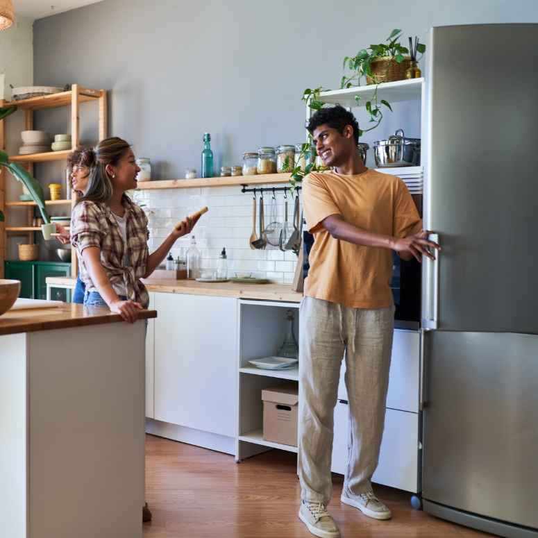 a man and a woman in a Scandinavian style kitchen while one opens a refrigerator.