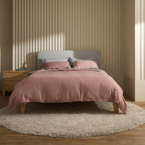 A bed with pink bedding in a semi-lit room.