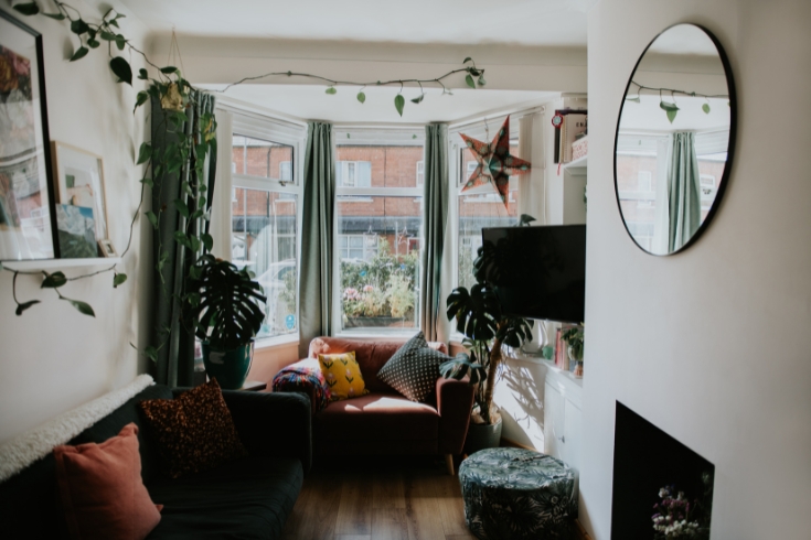 Small, cozy living room with a loveseat, TV and lots of plants.
