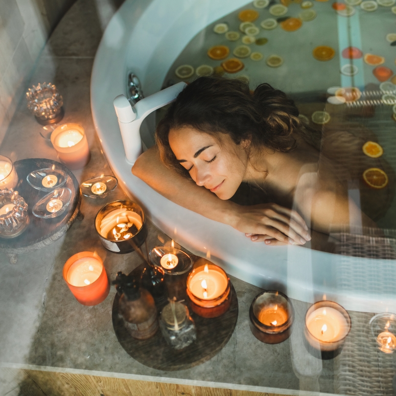 Woman sitting in bath with tropical fruits: lemons, limes and oranges in luxury bathroom.