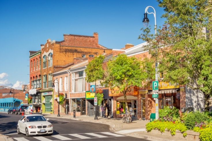 Car drives past stores in downtown St Catharines Ontario Canada on a sunny day