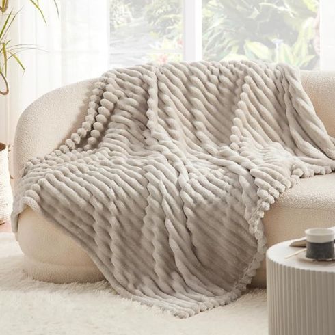 Grey fluffly fleece throw blanket on white sofa