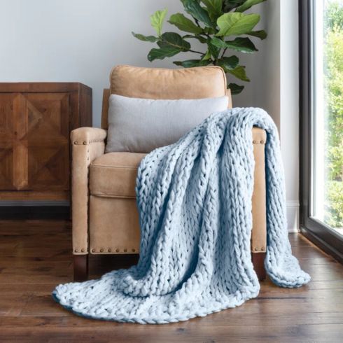 Chunky light blue throw blanket on light brown leather chair