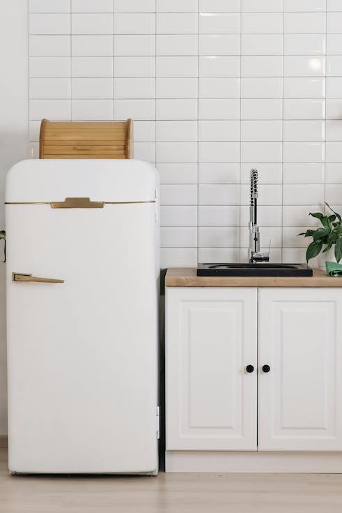 White Fridge Beside Kitchen Cabinet with Sink and white subway tile backsplash as part of HOME Networks Hidden Spots to Deep Clean in a Kitchen