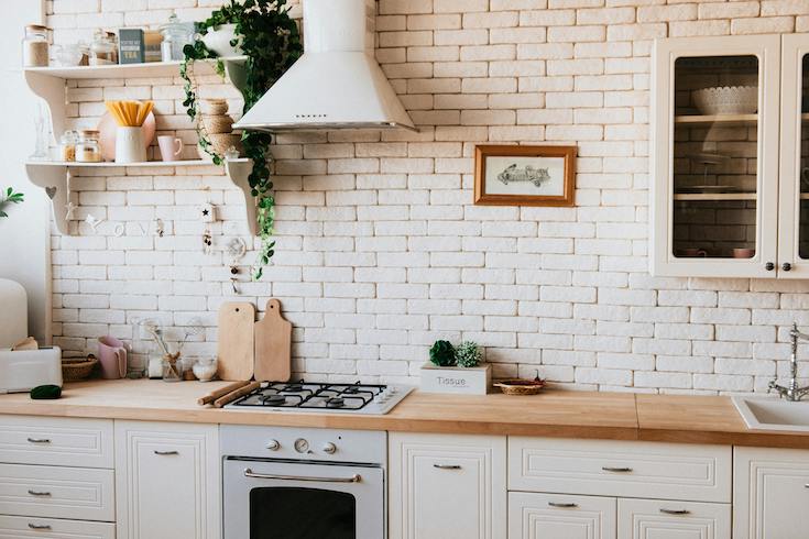 Chopping Boards Near Oven Under Hood in chic white kitchen with rough subway tile backsplash as part of a HOME Network post on the Hidden Spots in a Kitchen to Deep Clean