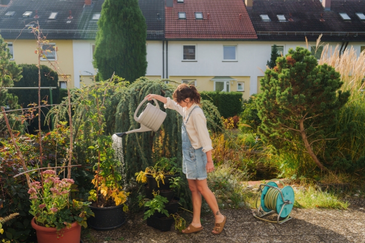 Serene woman watering plants on her backyard.