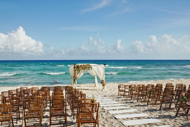 Chairs and wedding setup on the white sand Mexico with the ocean in the background.