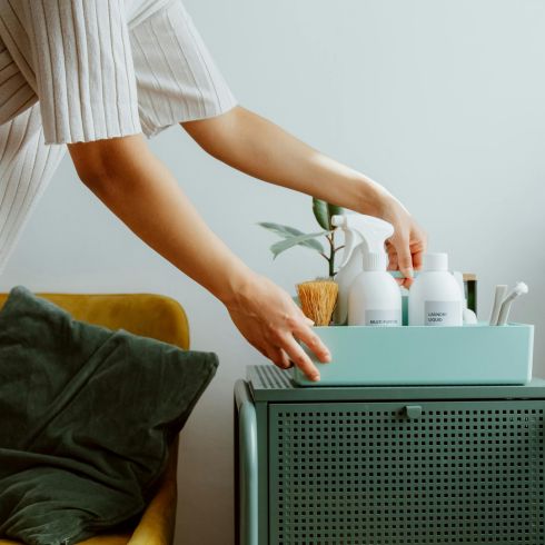 A woman organizes bath products in a small bin.