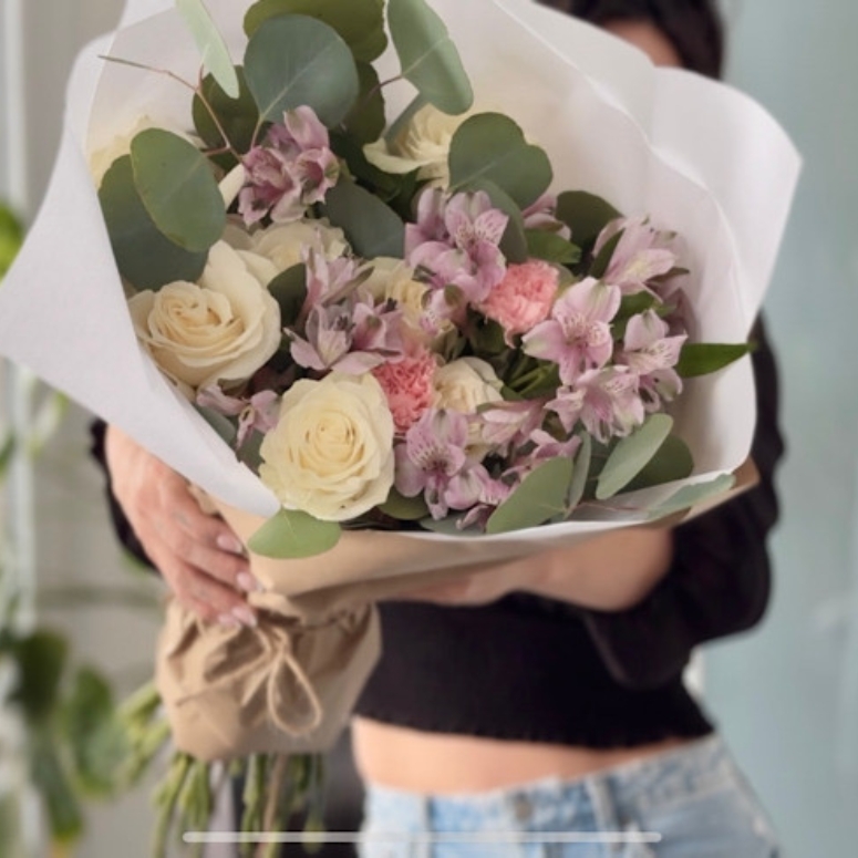 Creator holding up a beautifully wrapped bouquet of flowers.