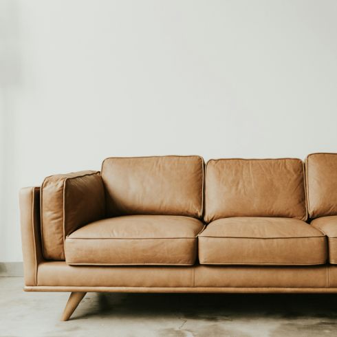 A tan leather couch with legs.