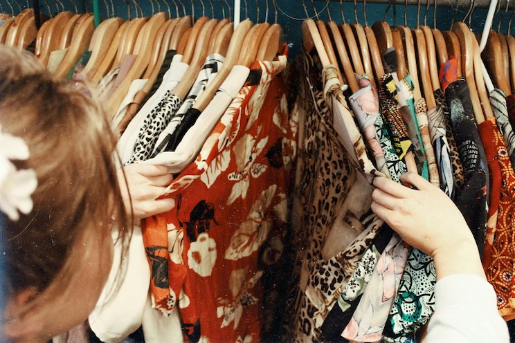A woman looking through hanging shirts