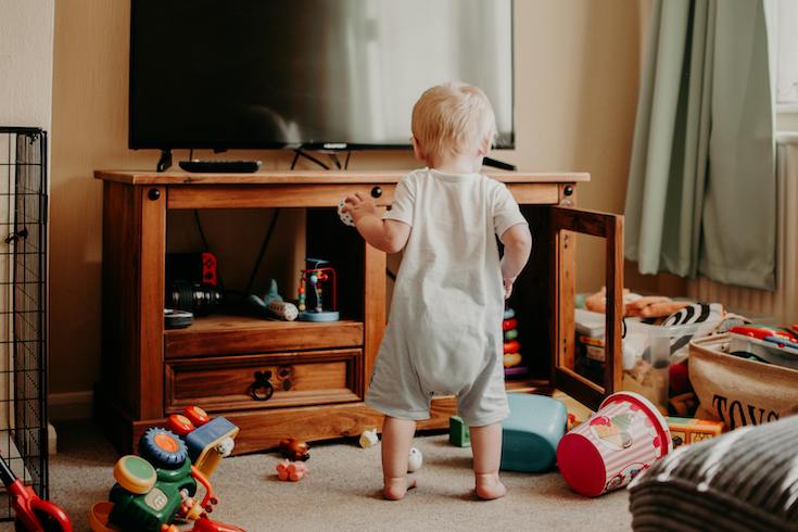 A Toddler Playing with in a messy living room for Home Network Viral Cleaning Routine post