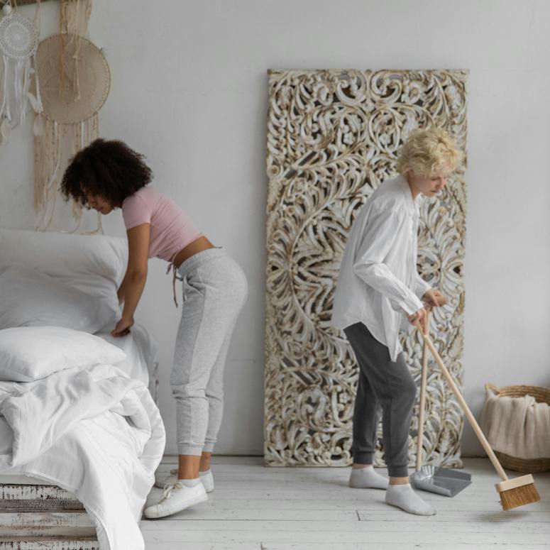 Two young Women Cleaning a white Bedroom