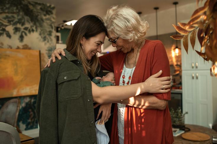 A Mother and grandmother Hugging a Newborn Baby tucked into the mother's shirt