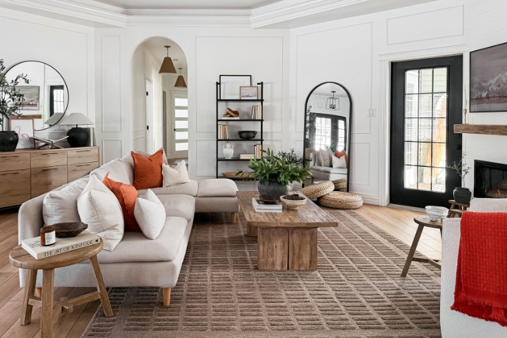 A bright, open living room featuring couch, coffee table, mirror and arched entrance.