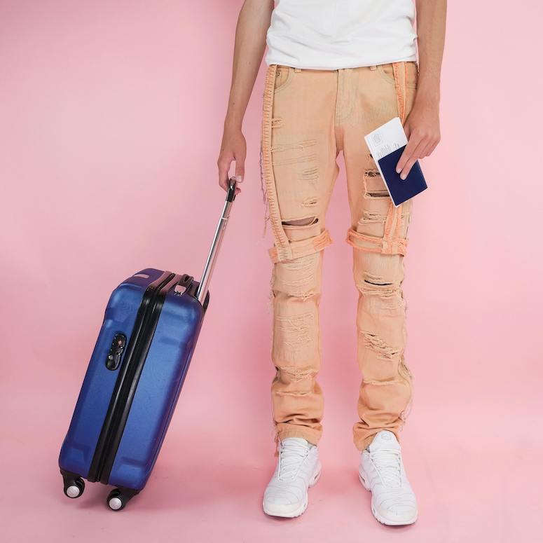 Person in White Tank Top and Brown Pants Carrying Blue and Black carry on case