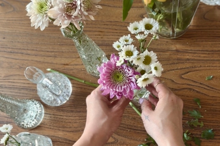 Pink and white flower stems being put into a vase.