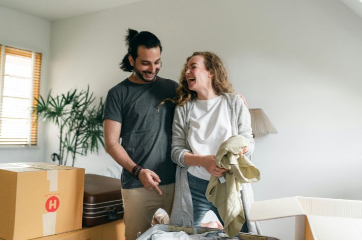 Excited couple unpacking boxes in a new apartment.