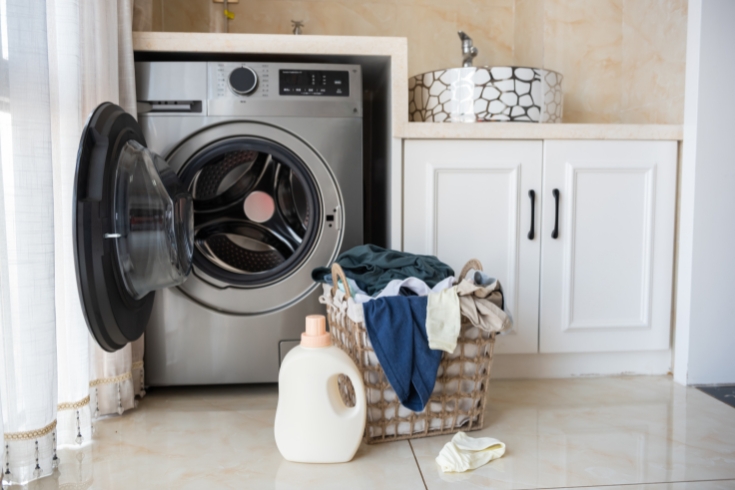 Basket with laundry and washing machine.