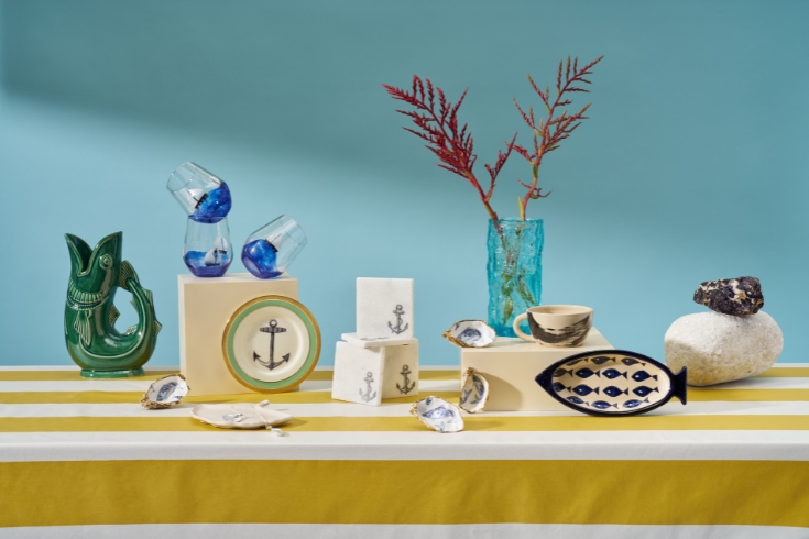 Display of plate and notebooks with anchor patter, fish vase and other fisherman-inspired items.