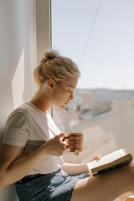 Woman in White Crew Neck T-shirt Holding Book.
