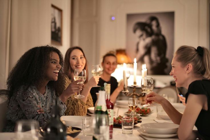 Women Holding Wine Glasses around a dining table as part of a post on how to do tablescaping for HOME Network