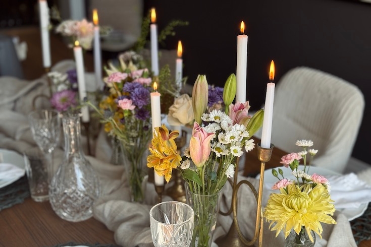 Flower centerpieces with candles on the table.