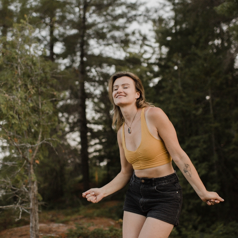 Woman dancing with eyes closed in forest.