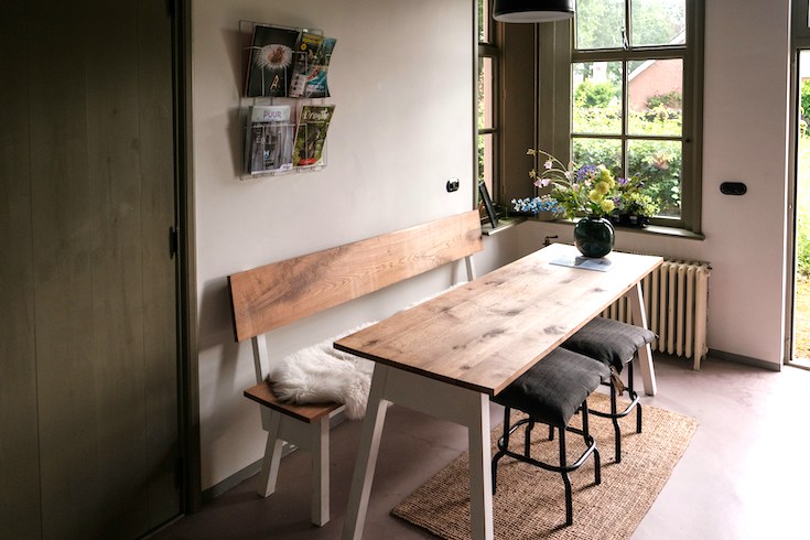 Wooden bench and table with a flower vase by an open door