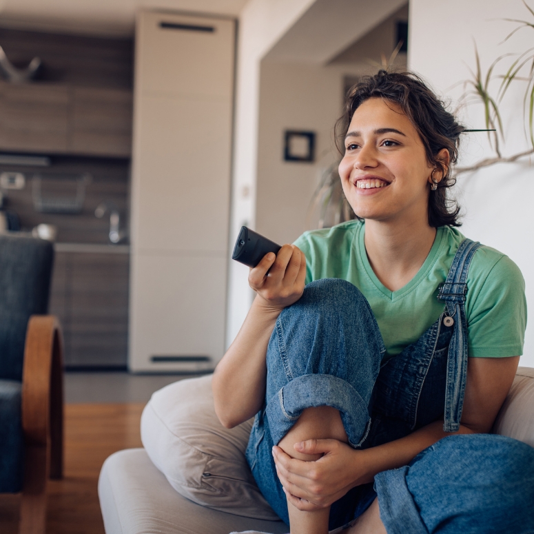 Young woman sitting on the sofa, watching TV at home and enjoying.