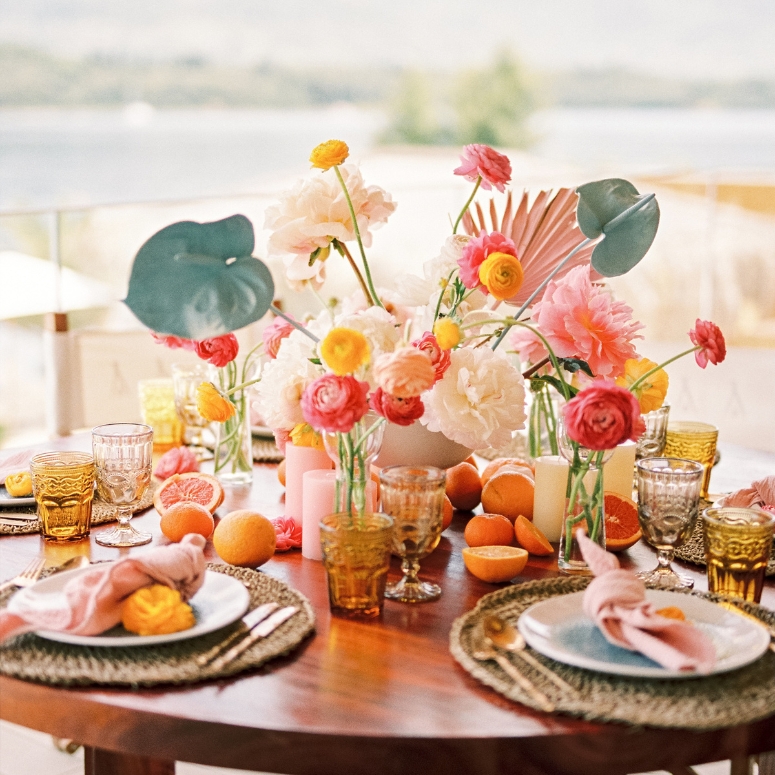 Plates with knotted napkins stand on mats on a table with a colorful bouquet.