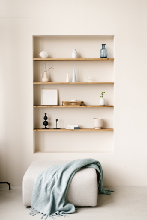 Built-in shelves in the wall with decor, personal accessories, ceramics in Scandinavian minimalist style.