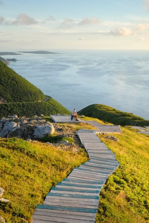 Man on wooden steps by sea, Cape Breton, Nova Scotia.