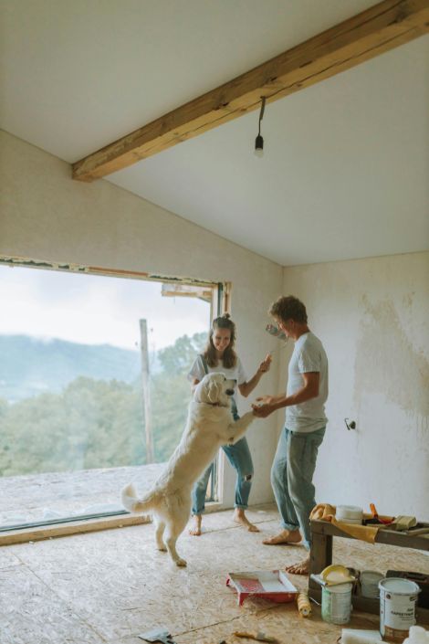 A couple happily plays with their dog in a house being renovated.