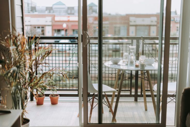 An outdoor patio with plants and a table with chairs. 