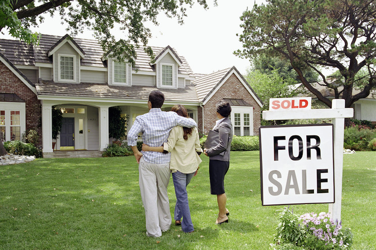 Real Estate Agent standing with couple in front of house