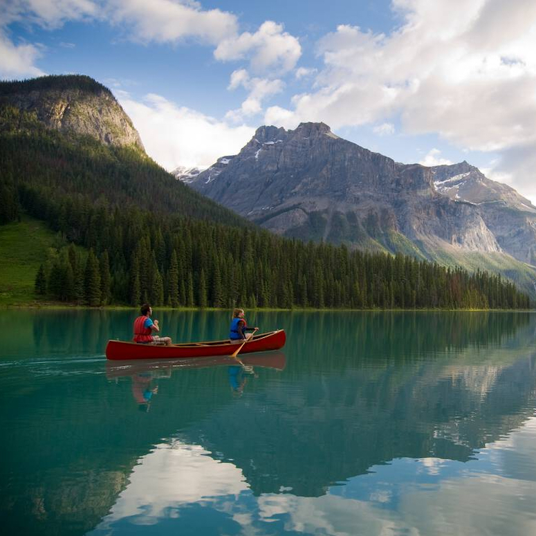 Two people canoeing on Emerald Lake with views of the mountains in Yoho National Park near Field.