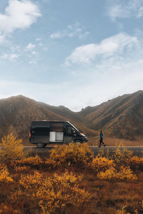 Overland Yukon Ram Promaster RV on the side of the road with a woman walking alongside in Canada's Yukon