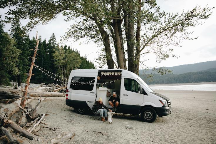 A Couple with an RV on a Beach with their dog and campsite decorations