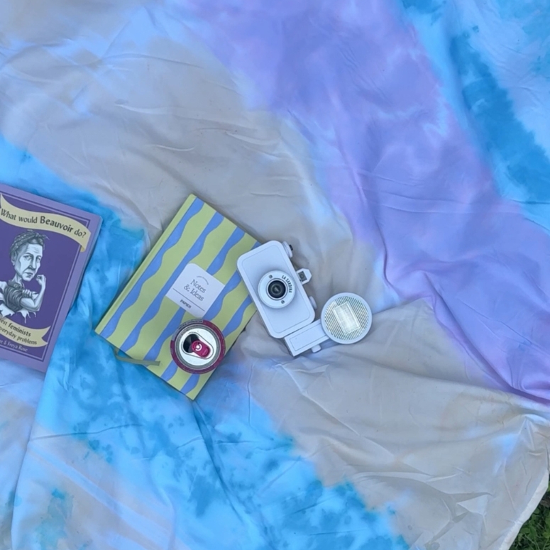 Final product of rainbow tie-dye blanket with books camera on top.