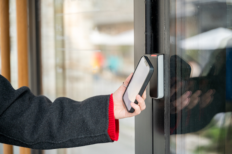 Hand holding smartphone opening door using smart digital lock. Integration of smart technology into everyday life