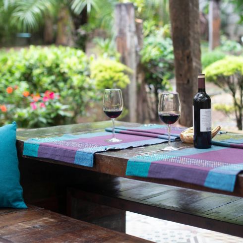 Purple and blue placemats and throw pillows placed on an outdoor picnic table.