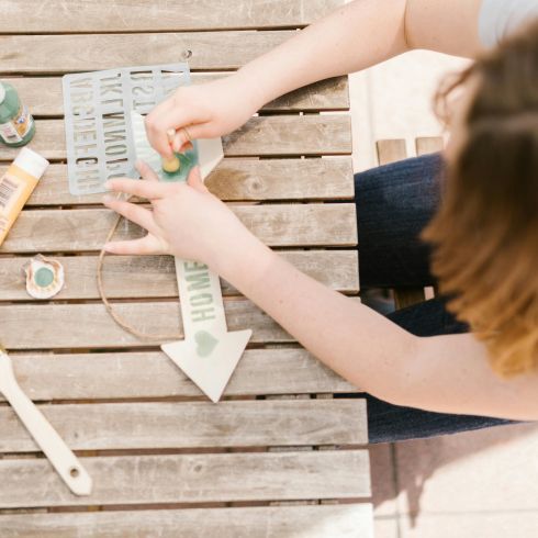 A person using a stencil and paints to decorate their outdoor space.