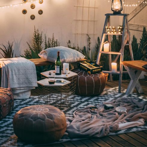 A backyard with comfortable sitting placed on top of a black and white outdoor rug.