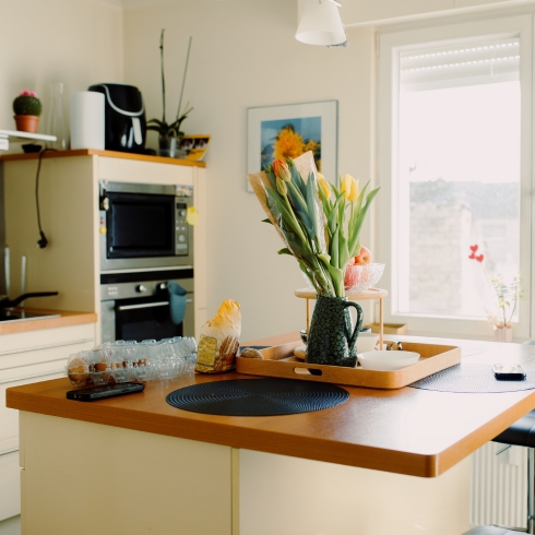 Just Add Some Flowers Cozy modern white kitchen on sunny day with tulips on table