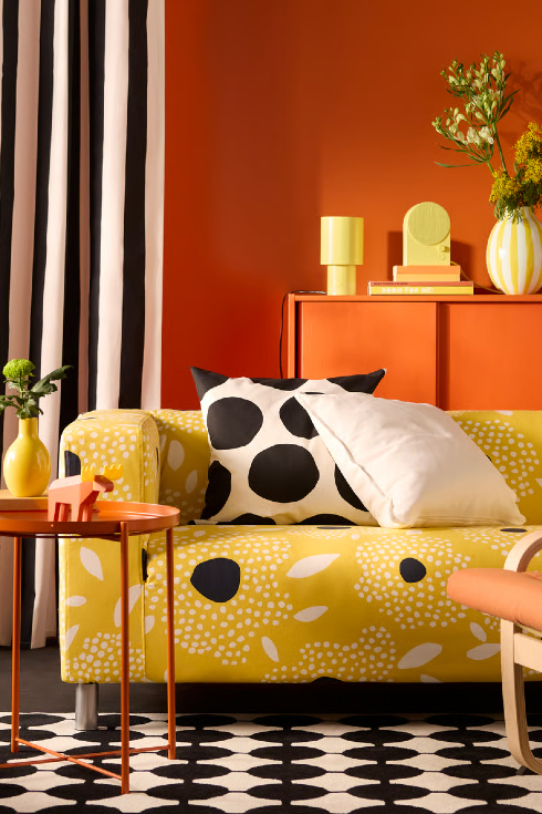 A room with various patterns: a dotted carpet, polka dot pillow, striped curtain and patterned couch