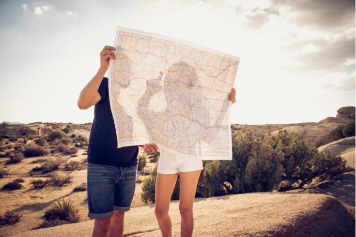 A couple reading physical map in desert.
