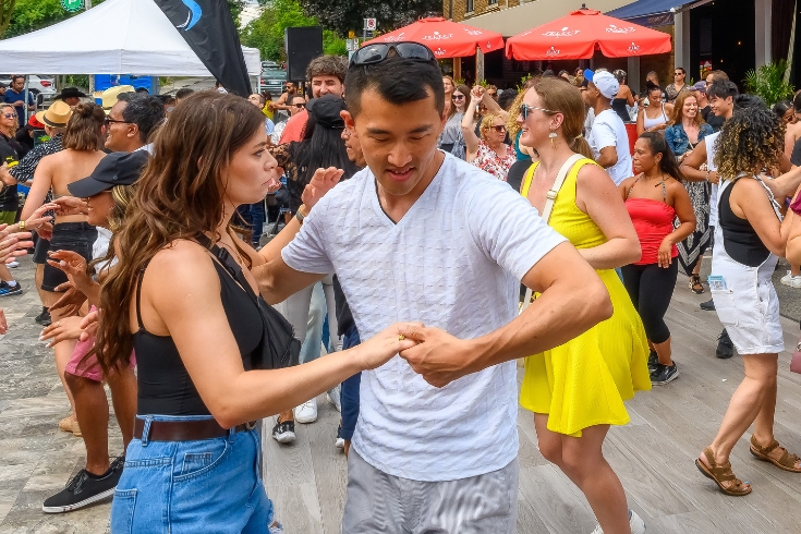 A dancing couple amid other people in the street. Salsa on Saint Clair Festival is a popular annual event in Toronto.
