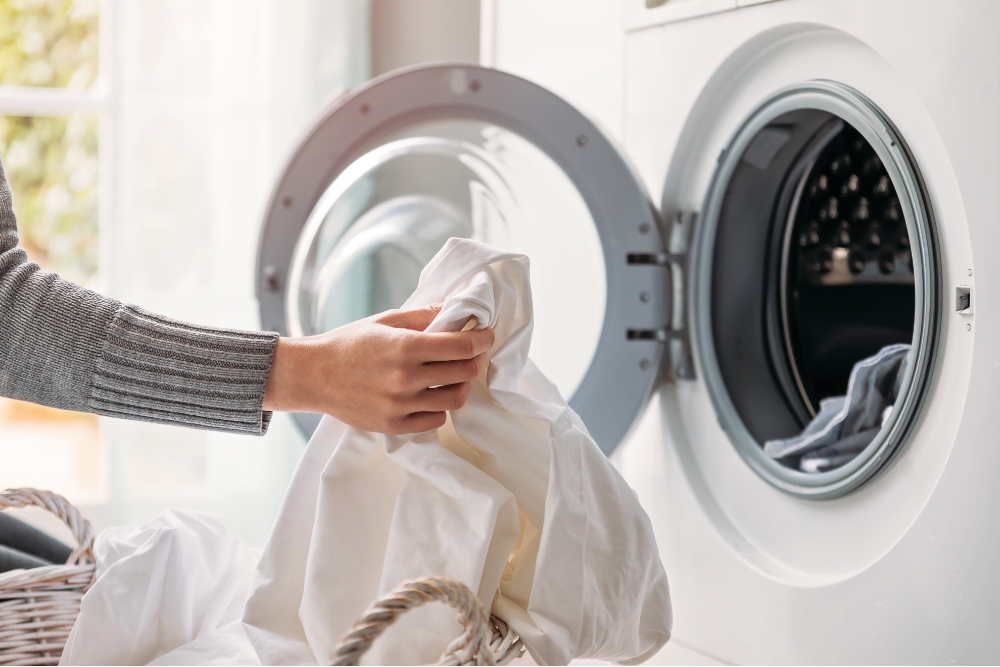 Close up of female hands dropping dirty laundry in the washing machine